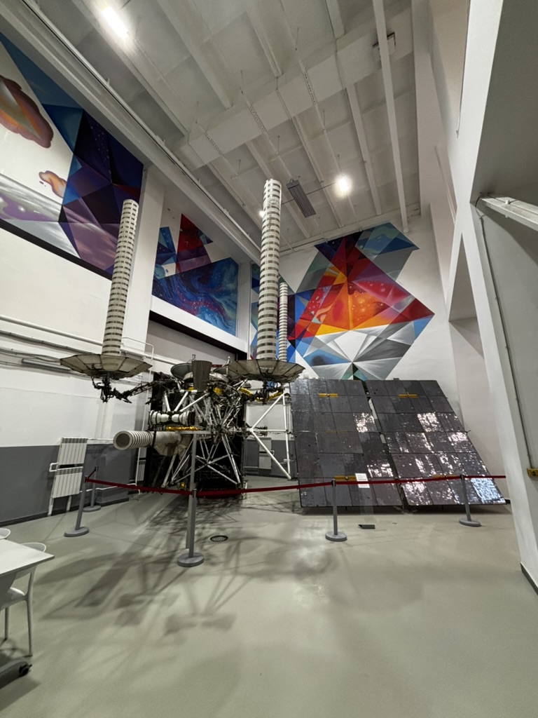 A spacecraft exhibit with solar panels in an exhibition hall