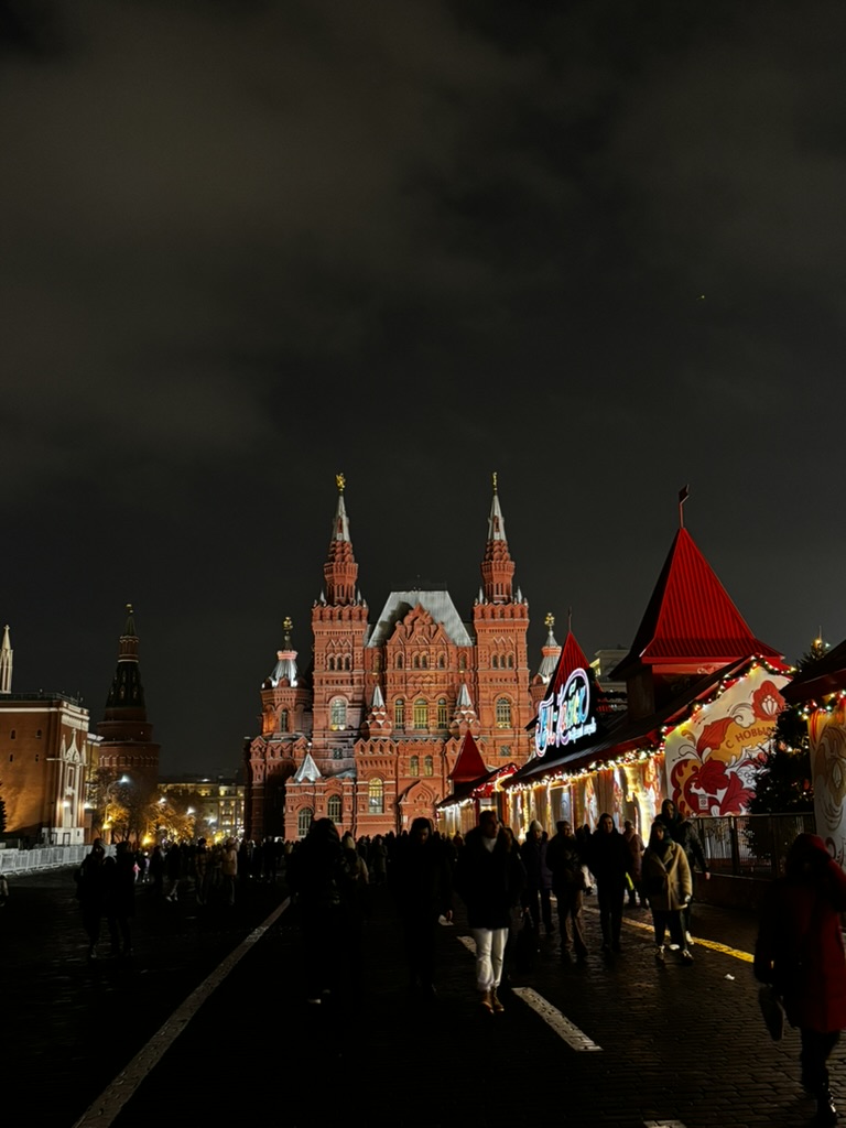 Visitors walking past illuminated buildings and market stalls at night