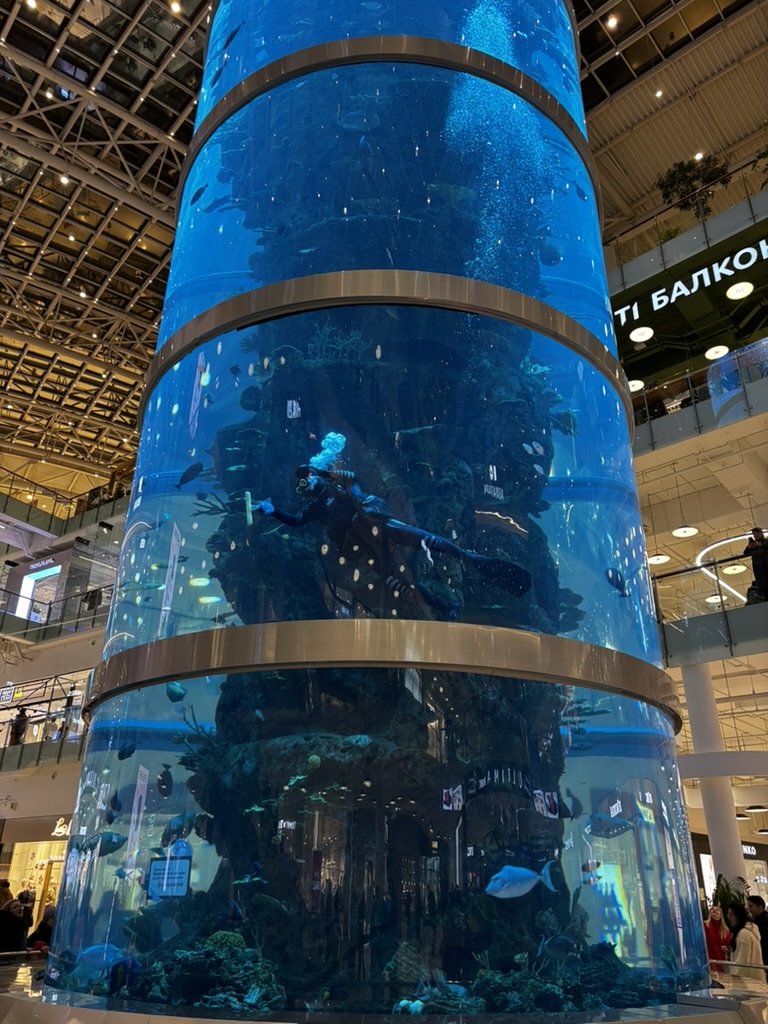 A tall cylindrical aquarium in a shopping center