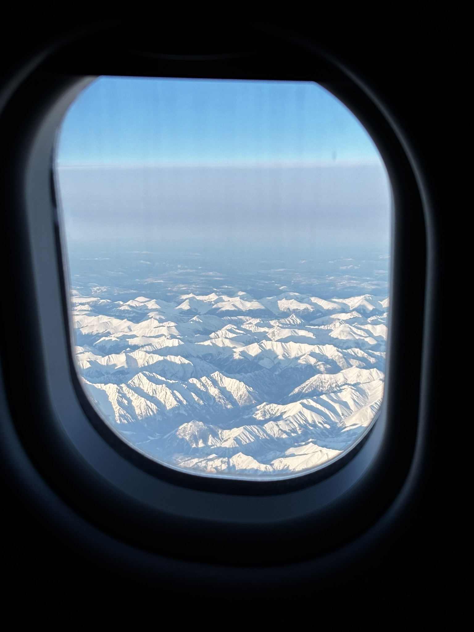 Snow-covered mountains seen through an aircraft window